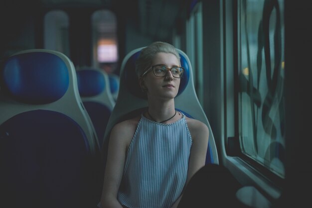 halbe Länge eines jungen hübschen kaukasischen blonden italienischen Designers, der in einem Zug sitzt