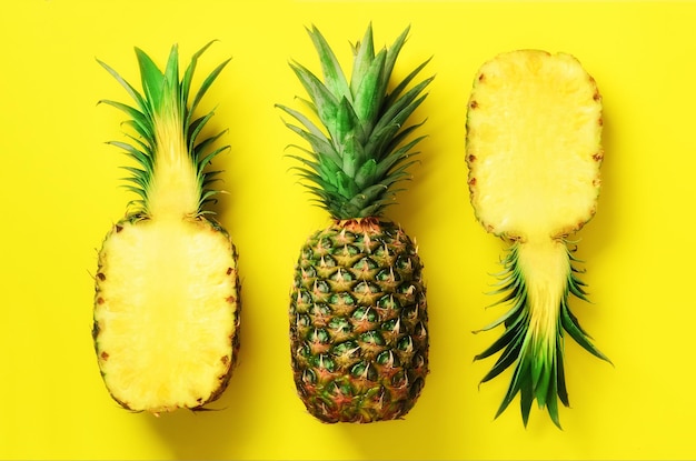 Halbe Scheibe frische Ananas und ganze Früchte auf gelbem Hintergrund Draufsicht Kopierbereich Helles Ananasmuster für minimalen Stil Kreatives Konzept des Pop-Art-Designs