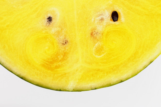 Halbe Scheiben der geschmackvollen und reifen gelben Wassermelone auf einer weißen, lokalisierten Beschaffenheit der saftigen Masse