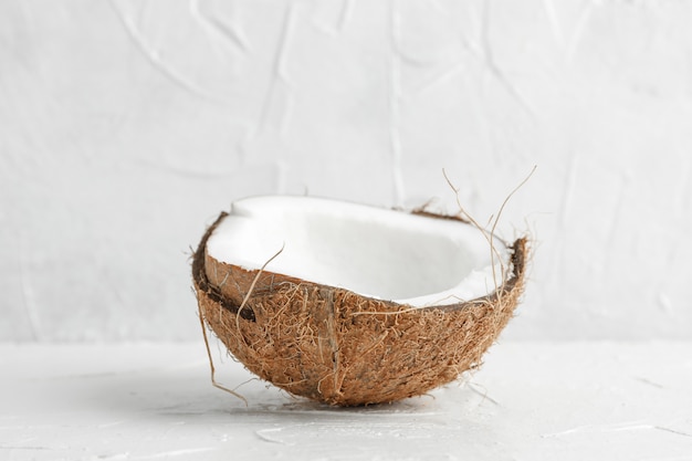 Halbe tropische Kokosnuss auf Holztisch gegen Weiß