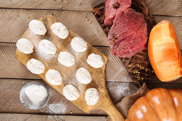 Halbfertige Manti-Knödel auf dem Holzbrett