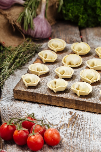 Halbfertige Pelmeni-Knödel auf Holzbrett