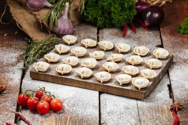 Halbfertige Pelmeni-Knödel auf Holzbrett