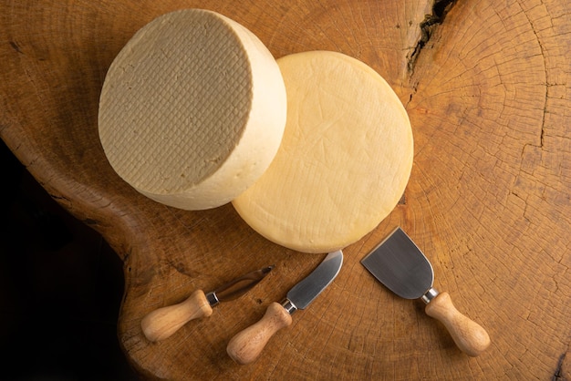 Halbgereifter Käse aus Brasilien, schöne brasilianische Käse und Schneidezubehör auf hellem rustikalem Holz, selektiver Fokus.