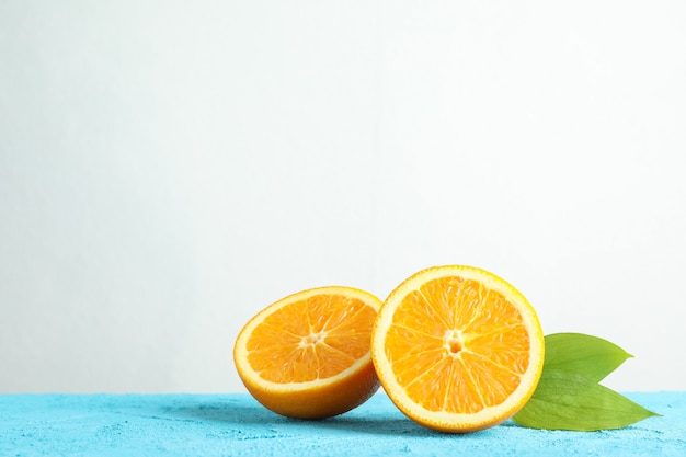 Halbiert Orange mit Blättern auf blauem Tisch vor weißem Hintergrund, Platz für Text