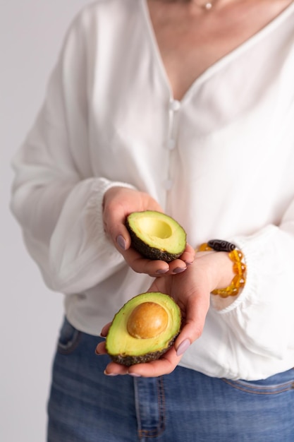 Halbierte Avocado in Frauenhänden Inhalt für Social-Network-Blog über gesunde Ernährung Helles vertikales Foto für einen Ernährungswissenschaftler über die Vorteile von Avocado