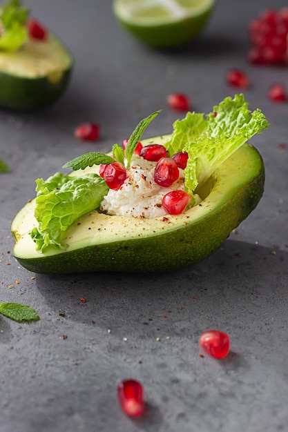 Foto halbierte avocado mit creme-käse, granatapfel-samen, salat, minze und limette, gesundes lebensmittelkonzept