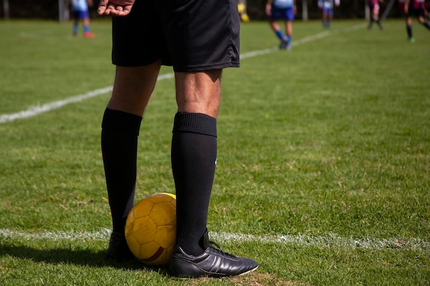 Halbkörper-Fußballschiedsrichter steht Rücken an Rücken mit einem gelben Ball zwischen seinen Beinen