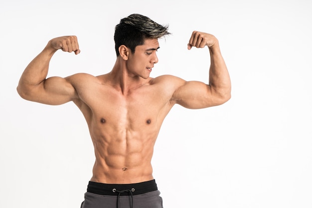 Halbkörperbild des jungen Mannes, der muskulösen Bizeps zeigt, steht nach vorne