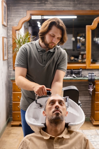 Halbnahe Einstellung eines Friseurs, der einem Mann die Haare wäscht