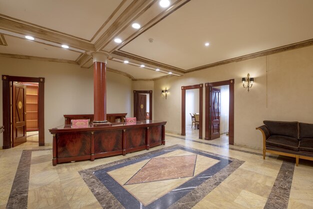 Hall de um escritório profissional com móveis de madeira e pisos de mármore de cores diferentes