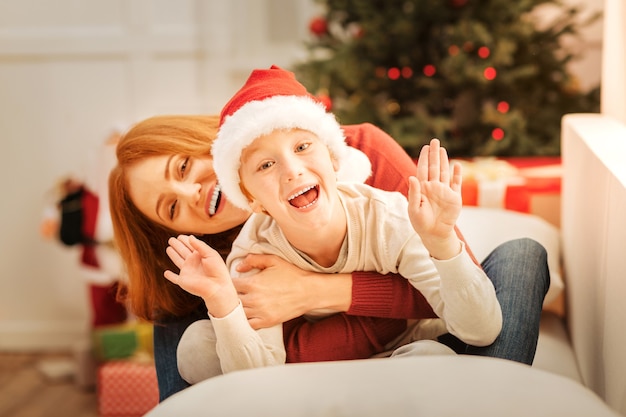 Hallo. Die entzückende Familie kann ihre Gefühle nicht im Haus behalten, während sie sich auf einem Sofa entspannt und an einem Weihnachtsmorgen scherzt.