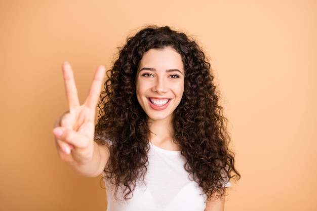 Hallo wundervolle Welt! Nahaufnahmefoto der erstaunlichen Dame, die V-Zeichen Symbol positive Stimmung tragen weiß lässiges Outfit isoliert beige Pastellfarbe Hintergrund zeigt