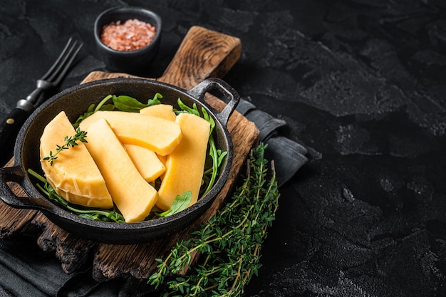 Halloumi-Käse in der Pfanne bereit zum Grillen. Schwarzer Hintergrund. Ansicht von oben. Platz kopieren.