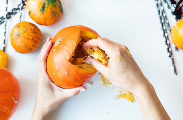 Halloween 31. Oktober. Der Schritt für Schritt zum Schnitzen eines Kürbisses. Das Mädchen bekommt Samen vom Kürbis. Sicht von oben.