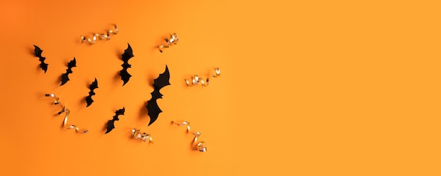 Halloween-Banner mit schwarzen Fledermäusen auf orangefarbenem Hintergrund, Ansicht von oben. Poster, Gutschein, Angebot, Gutschein, Ferienverkauf.