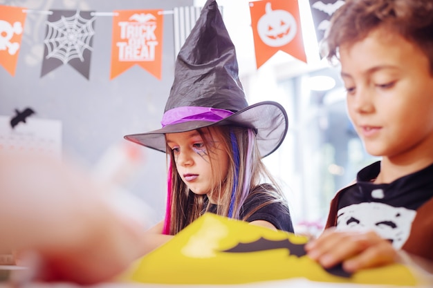 Foto halloween bilder. netter gutaussehender bruder und schwester, die beschäftigt fühlen, während sie halloween-bilder zusammen zeichnen