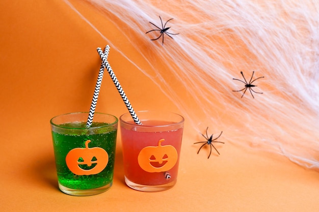 Halloween-Cocktailgetränke auf orangefarbenem Hintergrund mit Spinnen