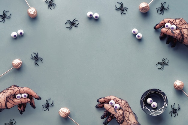 Halloween criativo plana leigos em cinza, rosa e preto com abóboras decorativas e aranhas. Mãos em luvas de malha preta imitando monstros. Cenário de Halloween de papel cinza com cópia-espaço