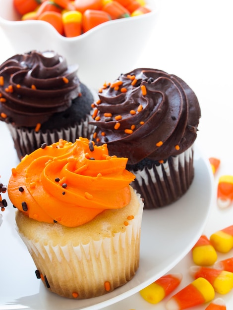 Halloween-Cupcakes mit orangefarbener und schwarzer Zuckerglasur auf weißem Teller.