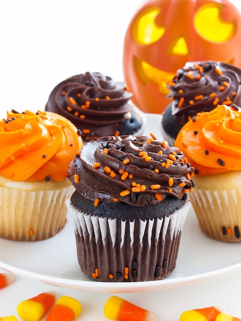 Halloween-Cupcakes mit orangefarbener und schwarzer Zuckerglasur auf weißem Teller.