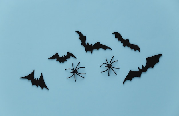 Halloween, decorações e conceito assustador. aranhas e morcegos pretos voam sobre o azul