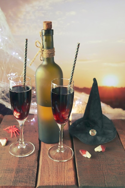 Halloween-Dekorationen, in Gläsern ein Cocktail aus Rotwein, Beleuchtung, Landschaft mit Sonnenuntergang