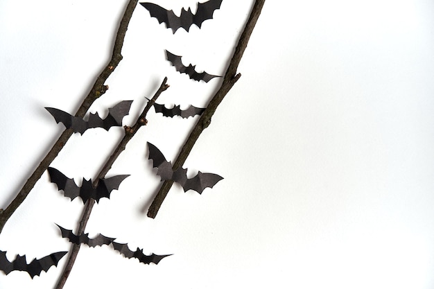 Foto halloween-dekorationskonzept schwarzes papier fledermäuse trockener zweigstock weißer kartonhintergrund