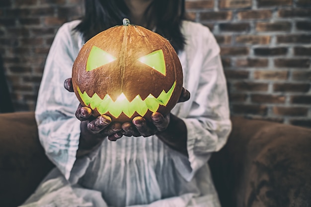 Halloween-Festival-Konzept. Geistermädchen im Blut mit dem weißen Kleid, welches das Halloween hält