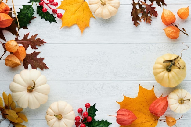 Halloween festlicher Herbsthintergrund Herbstdekor aus Kürbissen, Beeren, Ahornblättern und Kastanien auf alten rustikalen weißen Holzhintergründen Konzept des Erntedankfests Halloween Draufsicht kopieren Raum