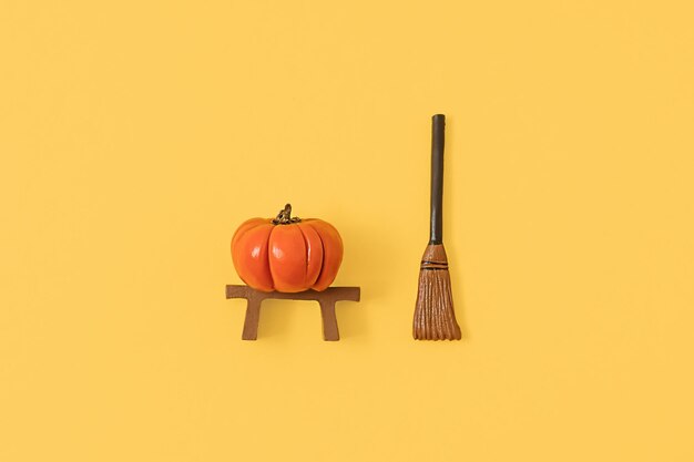 Foto halloween flat lay conceito feito de pequena abóbora laranja e vassoura de bruxa em fundo amarelo pastel idéia de outono minimalista visão superior criativa com espaço de cópia