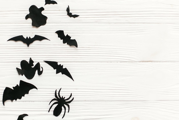 Foto halloween flat lay morcegos de papel preto aranhas fantasmas vista superior sobre fundo branco de madeira rústica travessuras espaço para texto modelo de cartão de saudação da temporada