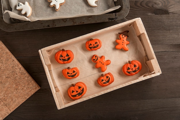 Halloween-Food-Konzept. Lustige orangefarbene Kekse in Form eines Kürbisses und Männer liegen in einer Form auf dem Tisch. Halloween-Leckerei