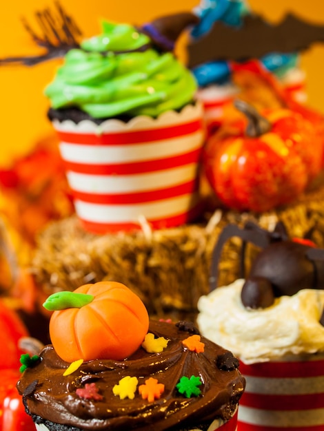 Halloween-Gourmet-Cupcakes mit orangefarbenem Hintergrund des Feiertagsdekors.