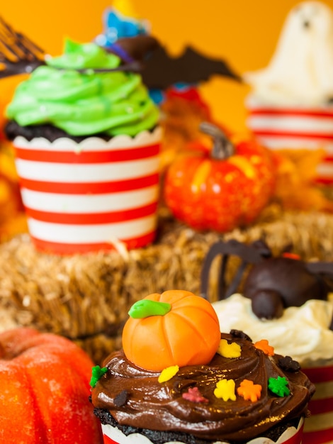 Halloween-Gourmet-Cupcakes mit orangefarbenem Hintergrund des Feiertagsdekors.