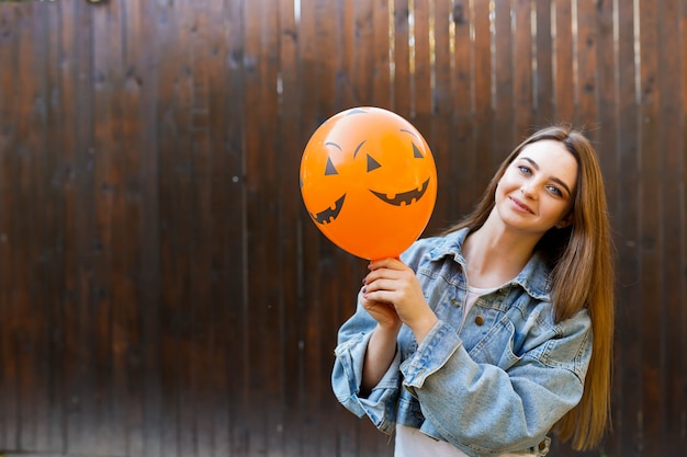 Halloween-Herbsthintergrund mit dem Mädchen, das orange Luftballon hält