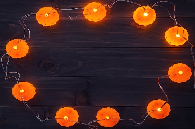Halloween-Hintergrund, Kürbis-Lichterketten auf Holztisch