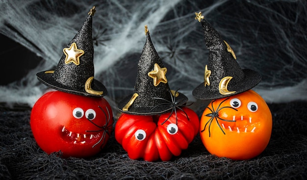 Halloween-Hintergrund Lustige Tomaten in Hexenhüten mit Spinnen auf dunklem Hintergrund Halloween-Essen Banner Kopieren Sie Platz