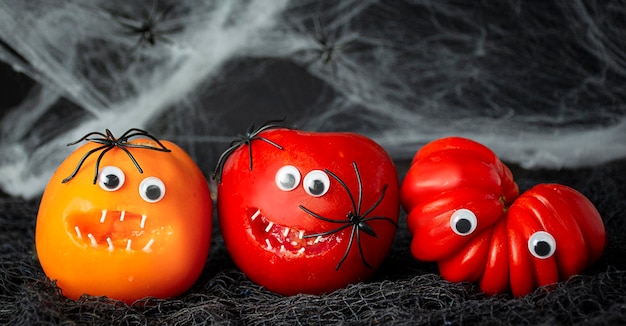 Halloween-Hintergrund Lustige Tomaten mit Spinnen auf dunklem Hintergrund Halloween-Essen Banner Kopieren Sie Platz