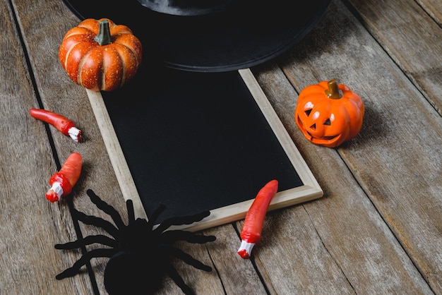 Halloween-Hintergrund mit Kürbisen, Hexenhut, Spinne, Fingern und Tafel