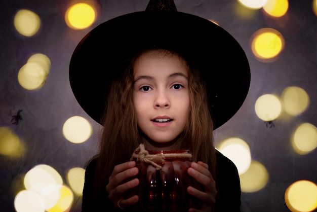 Halloween infantil Uma menina sorridente com uma jarra de vidro em forma