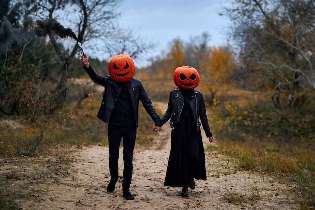 Halloween-Junge und Mädchen mit Kürbissen auf ihren Köpfen