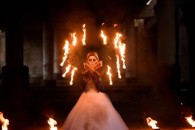 Halloween. Junges schönes Mädchen mit Make-up-Skelett auf ihrem Gesicht mit Feuer in ihren Händen.