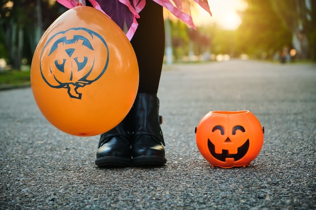 Halloween kinder. nahaufnahme der füße eines kindes mit kürbisbonbon-eimer.