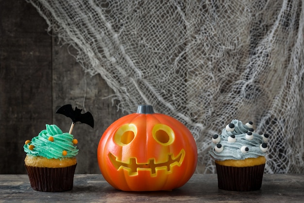 Halloween-kleine Kuchen und -kürbis auf Holztisch