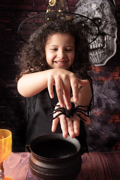 Halloween, kleines Mädchen, das in einer Halloween-Einstellung mit ihrer kleinen Spinnenfreundin spielt, selektiver Fokus.