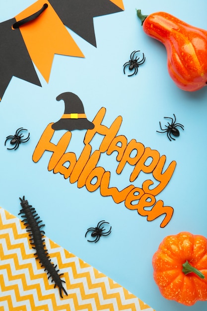 Halloween-Komposition mit Spinnen und Kürbissen auf blauem Hintergrund. Ansicht von oben. Vertikales Foto.