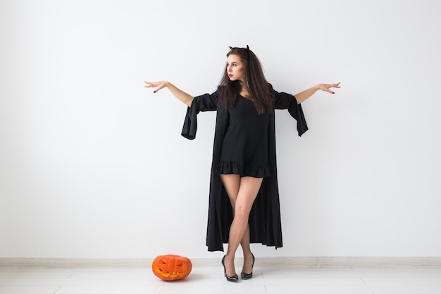 Halloween-Konzept - Glückliche Hexe mit Kürbis Jack-o'-Laterne auf hellem Hintergrund mit Kopienraum.