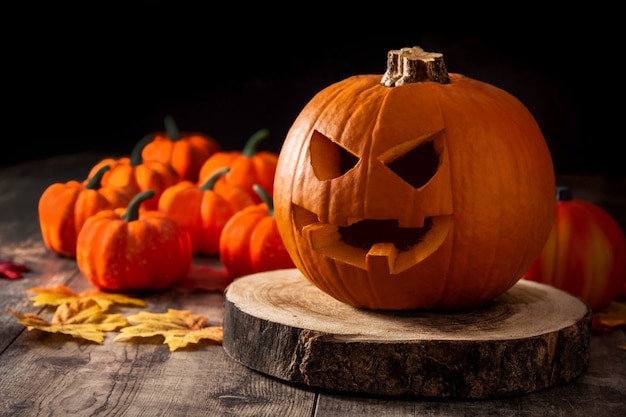 Halloween-Kürbis auf Holztisch und schwarzem Hintergrund