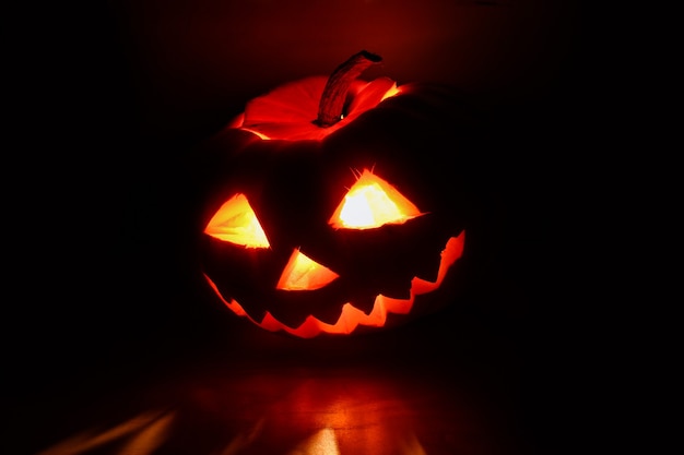 Halloween-Kürbis mit geschnitztem leuchtendem Gesicht im Dunkeln.